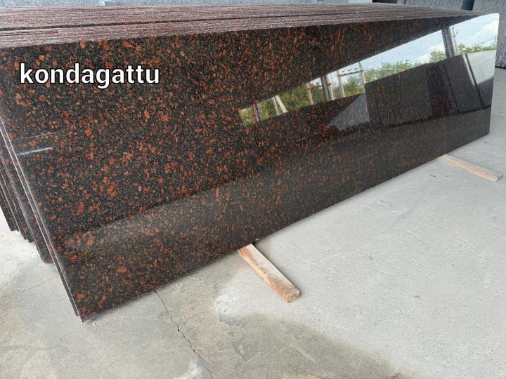 Stack of polished red-brown flecked granite slabs