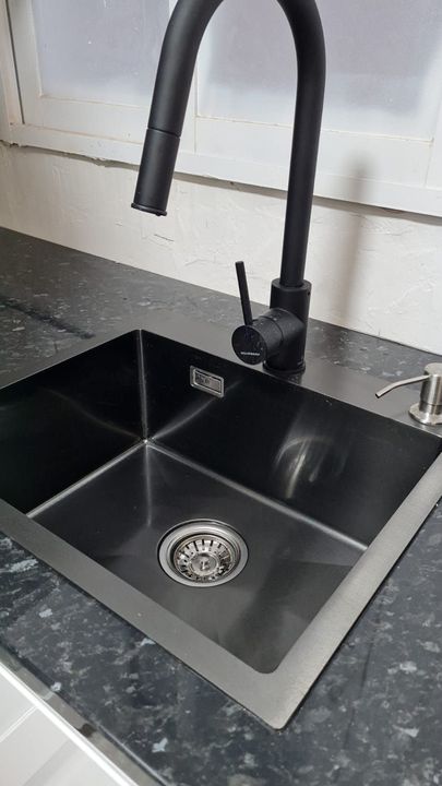 Black undermount sink and faucet set into dark granite